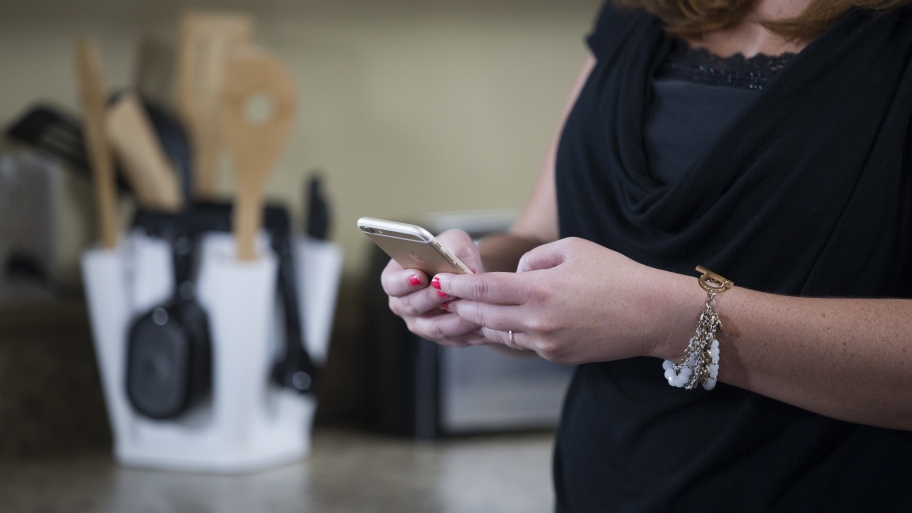 woman tapping on phone in kitchen